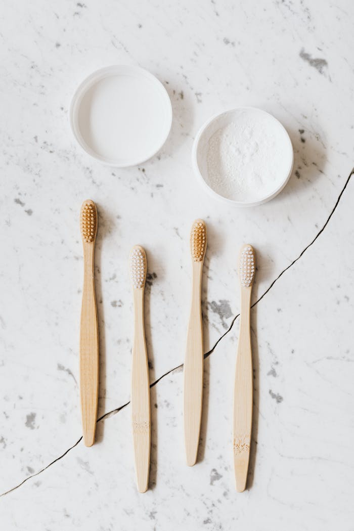 Home Top view layout of different various wooden brushes and tooth powder placed on chipped marble table