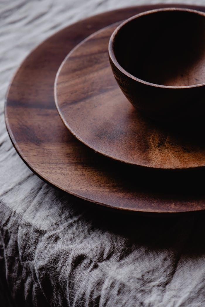 About Close-up of a rustic wooden bowl and plate set on a textured fabric surface, showcasing natural elegance.